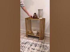 a person standing next to a table with vases on it and a rug in the background