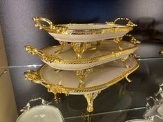 three tiered trays on display in a glass case with gold trimming and ornate designs