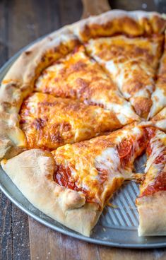 a pizza sitting on top of a metal pan covered in cheese and pepperoni slices