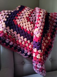 a crocheted blanket sitting on top of a couch next to a white chair