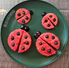 four slices of watermelon and black olives are arranged on a green plate