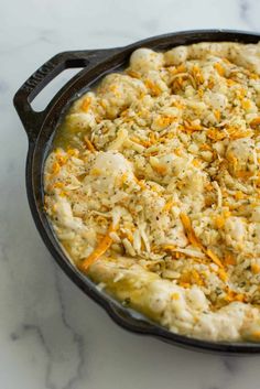 a casserole dish with chicken and cheese in it on a marble counter top