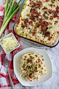 a casserole dish on a plate with green onions and cheese next to it