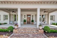 the front porch of a house with two planters on each side and one door open