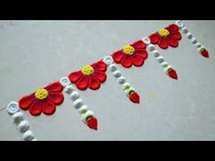 a red and yellow flower design on a white table cloth with beads around the edges