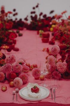 the table is covered with pink flowers and plates, silverware, and utensils