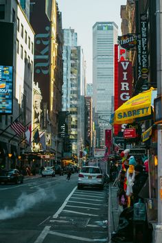 a city street filled with lots of tall buildings and cars driving down the road next to each other