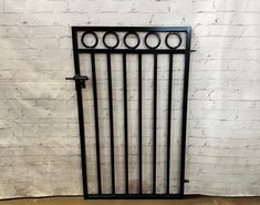 an iron gate on the ground in front of a white brick wall