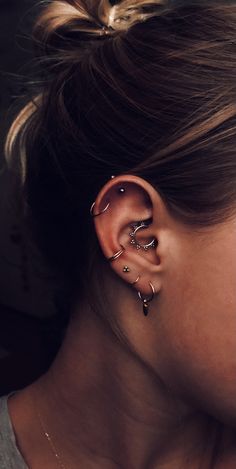 a woman's ear with three different types of piercings