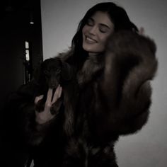 a woman in a fur coat holding a dog