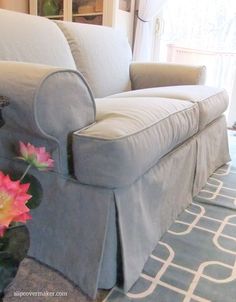 a living room with a couch, chair and flower vase on the floor in front of it