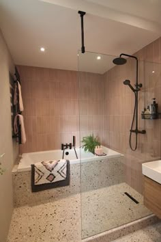 a bathroom with a walk in shower next to a white sink and bathtub filled with plants