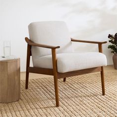 a white chair sitting on top of a wooden floor next to a vase filled with flowers