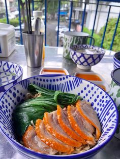 a bowl filled with meat and veggies on top of a table next to cups