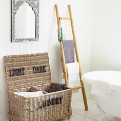 a white bath tub sitting next to a wicker basket filled with towels and other items