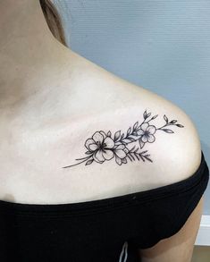 a woman's shoulder with flowers and leaves tattoo on her left side ribcage