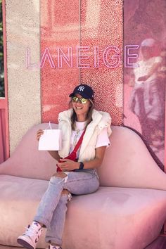 woman sitting on lips shaped couch holding a pink Laneige shopping bag Elf