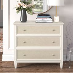 a white dresser with flowers and books on top