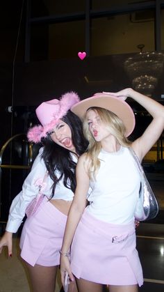 two young women dressed in pink posing for the camera