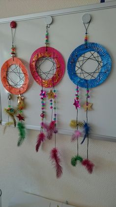 there are three circular objects hanging on the wall with beads and feathers attached to them