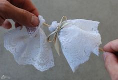 two hands holding small white lace bags tied with twine