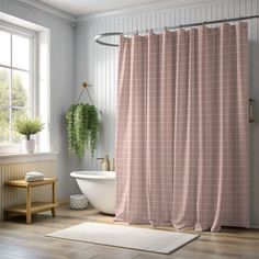 a bathroom with a pink shower curtain next to a white bath tub and wooden floor