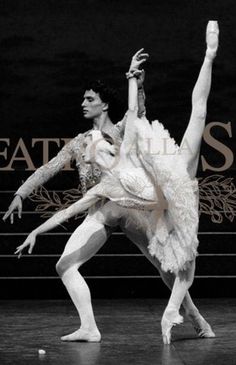 two ballerinas in white tutus and one is reaching up to the floor