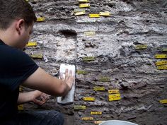 a man sitting on the ground next to a wall covered in yellow tags and papers