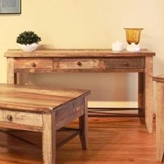 a wooden table sitting on top of a hard wood floor next to a white vase