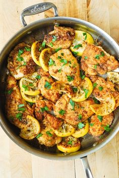 chicken with lemons and parsley in a skillet on a wooden table top