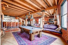 a billiard table in the middle of a room with purple couches and rugs