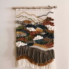 a wall hanging made out of different types of yarn and beads on a white wall