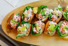 small sandwiches with lettuce and other toppings on a wooden platter, ready to be eaten