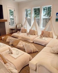 a living room filled with white couches and pillows on top of a carpeted floor