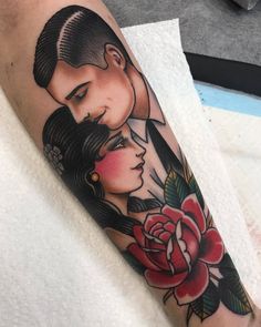 a man and woman face to face with a rose tattoo on their arm, both holding each other