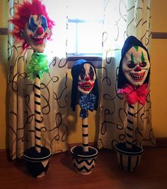 three creepy clowns sitting on top of planters in front of a window with curtains