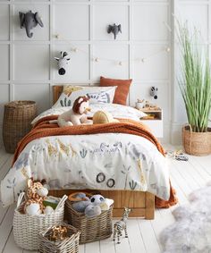 a child's bedroom with stuffed animals on the bed and toys in baskets next to it