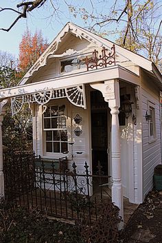 a small white house with an iron fence around it's front door and porch