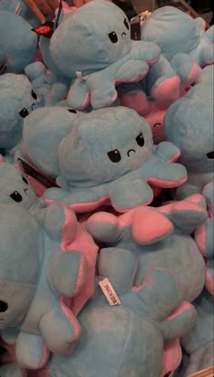 a pile of blue and pink stuffed animals sitting on top of each other in a store