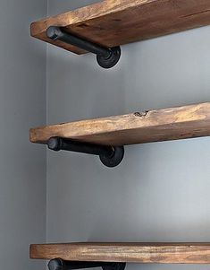 three wooden shelves with metal handles and knobs on each shelf, against a gray wall