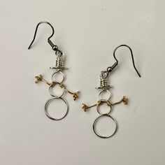 two pairs of silver and gold earrings on a white surface, one with an open loop