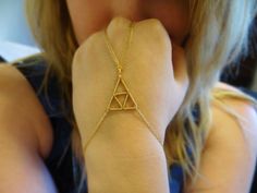 a woman wearing a gold bracelet with a triangle on it