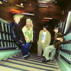 three people are standing on the stairs in an underground area, one is wearing a hat