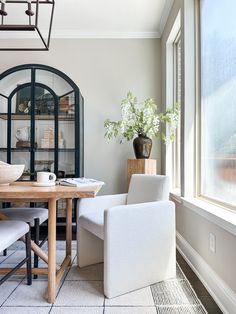 a dining room table with two chairs and a vase on top of it next to a window