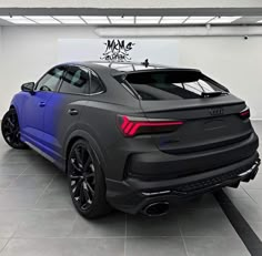 the rear end of a grey audi suv in a showroom with black rims