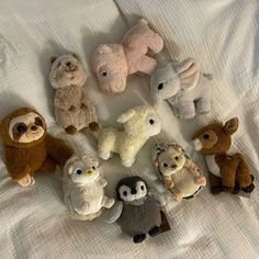 several stuffed animals are arranged in a circle on a white bed linens covered sheet