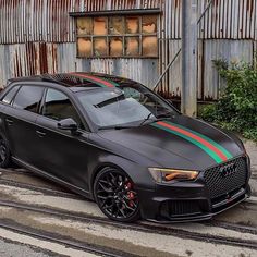 a black car with red, green and blue stripes parked on the side of a road