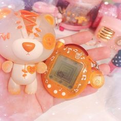 a hand holding a small electronic device in it's right hand, with an animal keychain attached to it