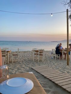 people are sitting at tables on the beach