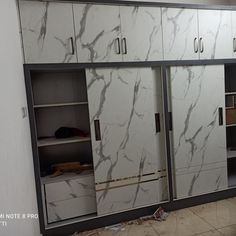 an empty room with white cabinets and marble flooring